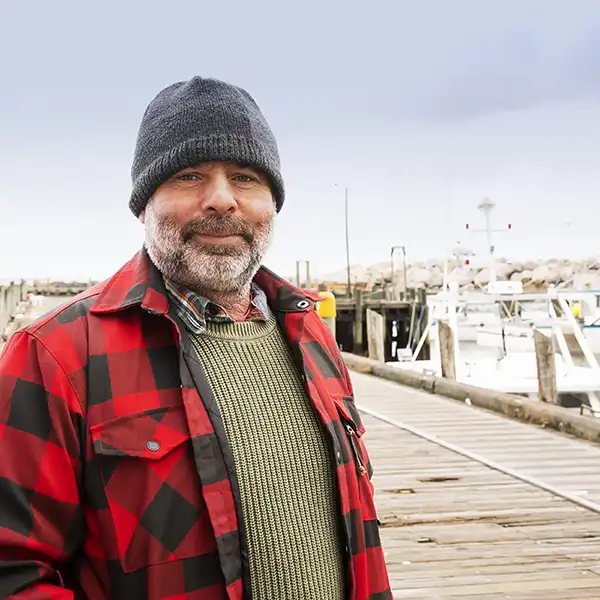 mature commercial fisherman on a wharf with fishing boats in background